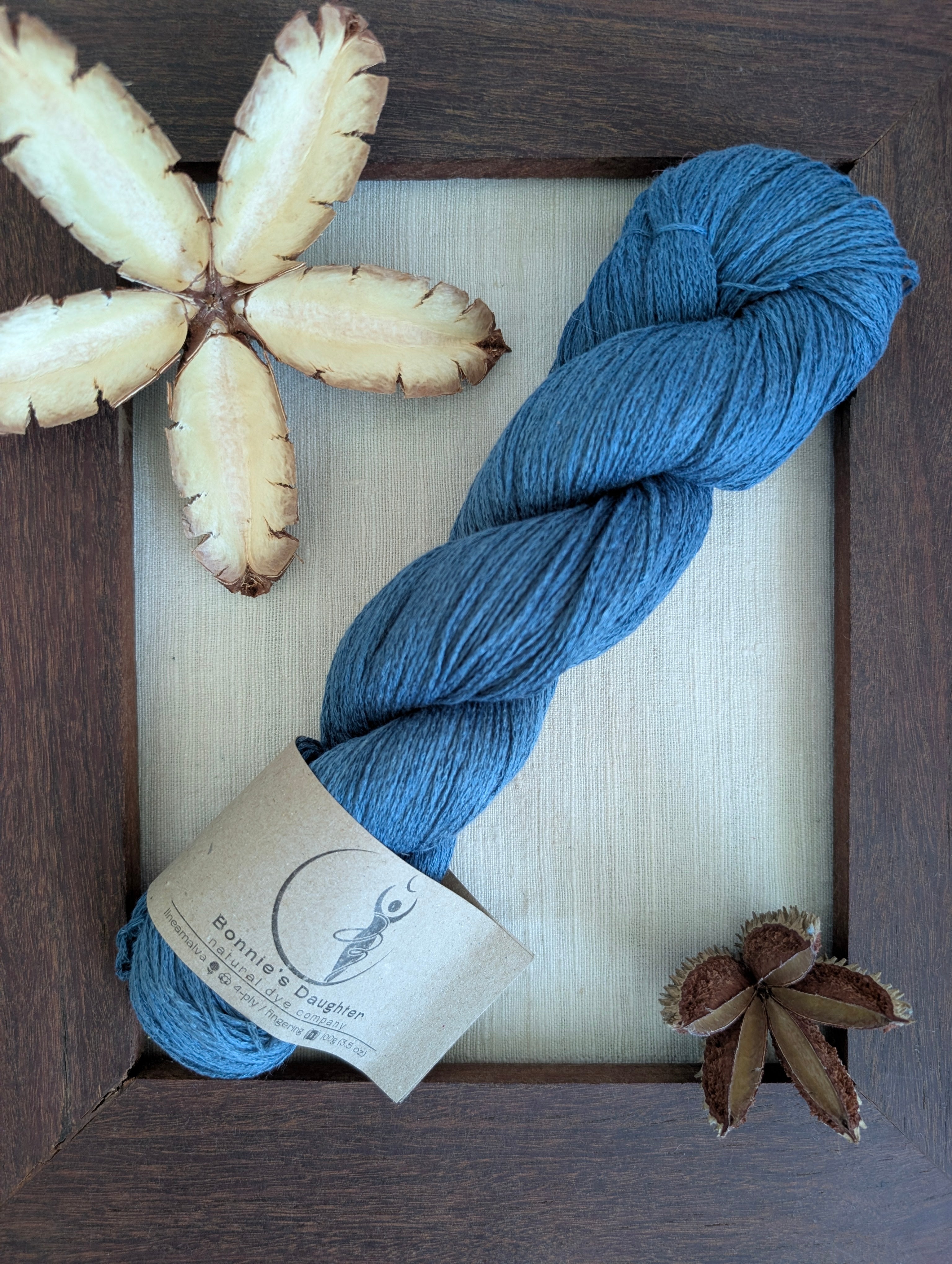 Blue skein of yarn with a label on a wooden surface with decorative elements