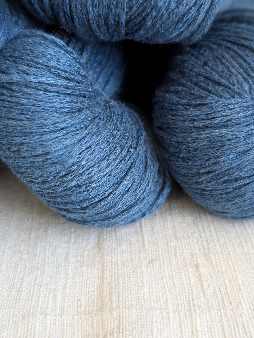 Three skeins of blue yarn on a light wooden surface