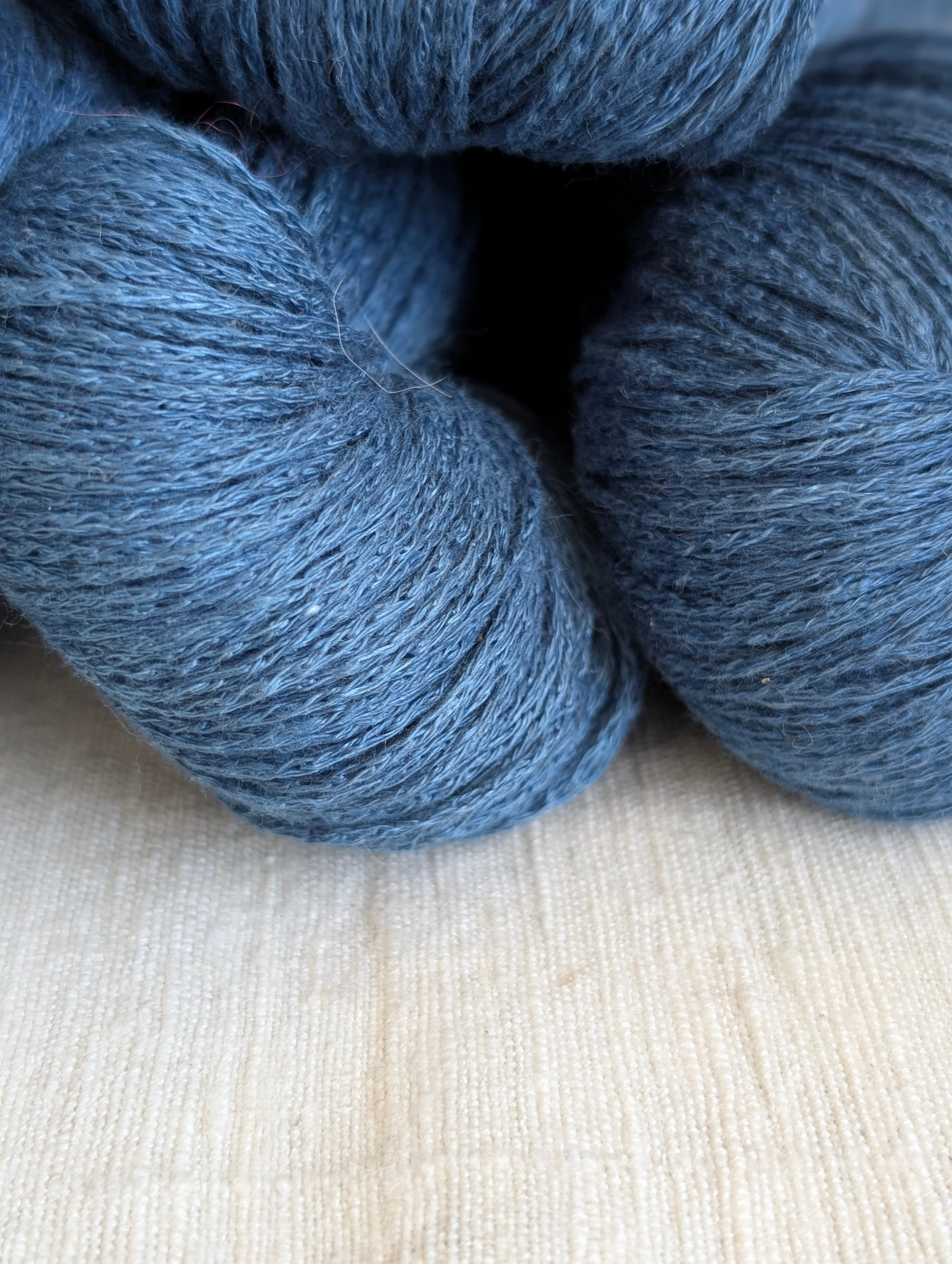 Three skeins of blue yarn on a light wooden surface